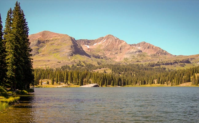 Mountain lake surrounded by pine trees and red peaks in Colorado